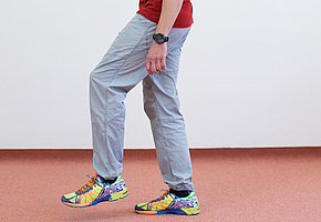 Mann steht in kleiner Schrittstellung mit dem linken Bein vorn, linker Fuß ist leicht vom Boden abgehoben.