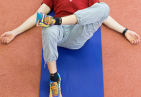 Mann liegt auf Matte auf dem Rücken, das rechte Bein ist aufgestellt, das linke mit dem Knöchel auf den rechten Oberschenkel gelegt