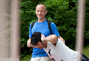 Ein Physiotherapeut hilft einem Patienten bei einer Gymnastikübung für den Rücken.